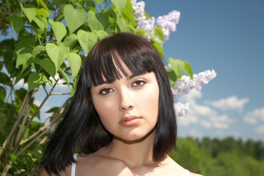 The girl against lilac bushes and sky 