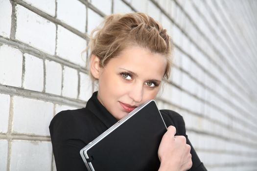 girl in  business suit and with the laptop against  wall from a brick