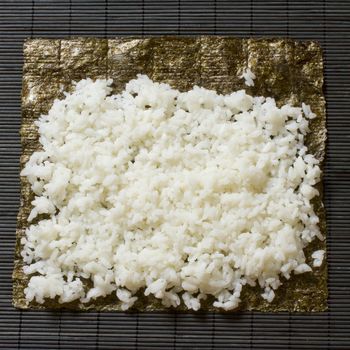 White rice laying over a seaweed for sushi