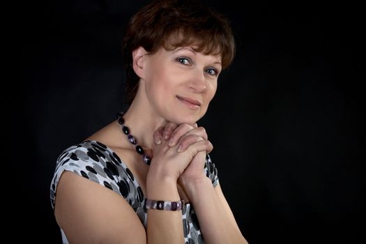 The smiling woman with  beads and  bracelet on  black background