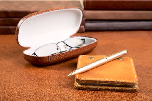 Notebook with  leather cover  pen and glasses on a textural background