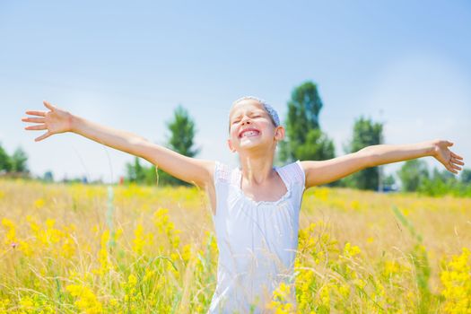 Adorable happy girl in yellow flowers field. Summer freedom andjoy concept.