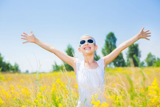 Adorable happy girl in glasses in flowers yellow field. Summer freedom andjoy concept.