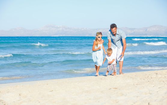 Happy family of three sitting and having fun on tropical beach