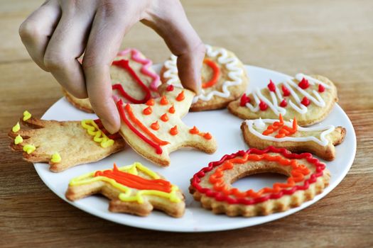 Hand taking cookie from plate of homemade shortbread cookies with icing