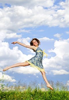 Young teenage girl jumping in summer meadow amid wildflowers