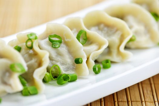 Plate of cooked chinese dumplings in a row