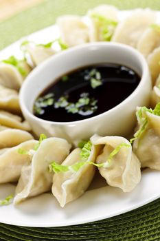 Closeup on plate of steamed dumplings with soy sauce