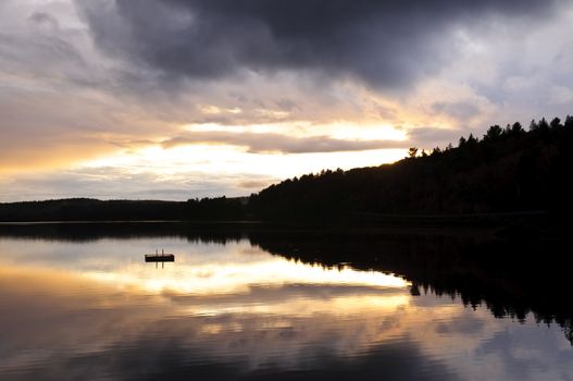 Sun setting over tranquil lake and forest