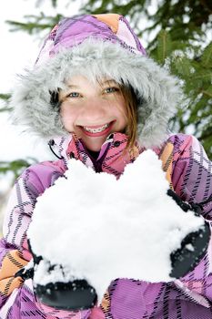 Portrait of happy teenage girl holding snow in gloves