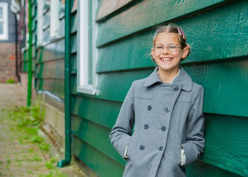 Young girl near green wooden wall looking at the camera