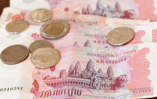 Five hundred riel notes from Cambodia with coins from Thailand