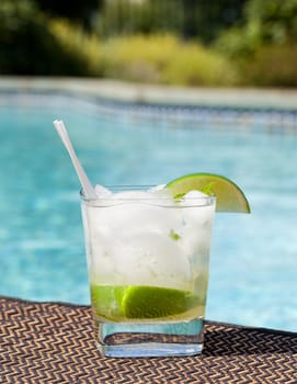 Glass of ice cold majito in glass by side of swimming pool