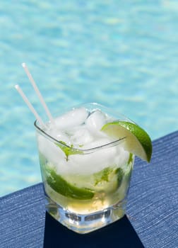 Glass of ice cold majito in glass by side of swimming pool