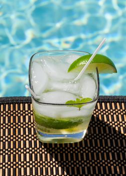 Glass of ice cold majito in glass by side of swimming pool