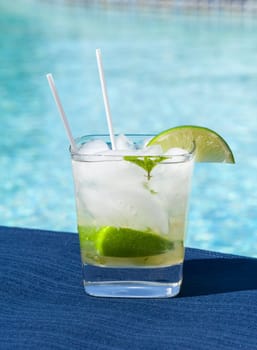 Glass of ice cold majito in glass by side of swimming pool