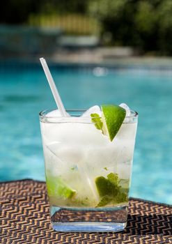 Glass of ice cold majito in glass by side of swimming pool