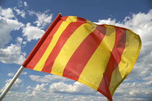 The orange striped flag on a background of the dark blue sky with clouds is yellow.