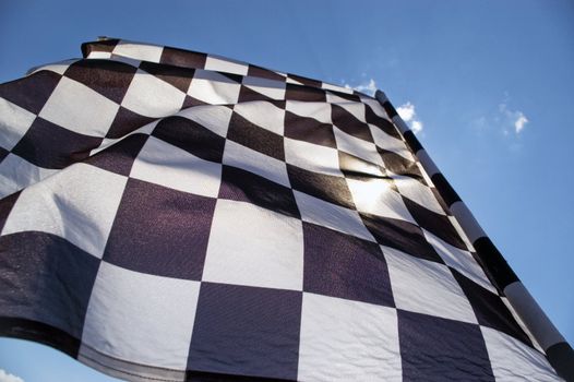 Auto racing checkered flag on a background of the  blue sky.