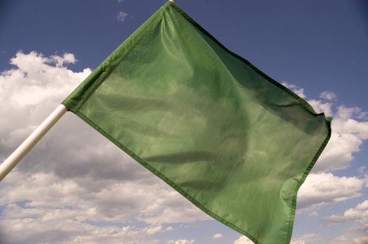 Green flag on a background of the dark blue sky with clouds.