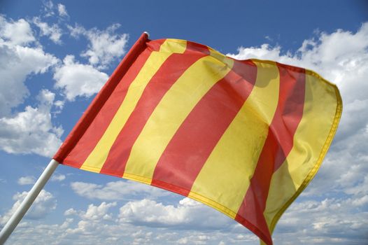 The orange striped flag on a background of the dark blue sky with clouds is yellow .