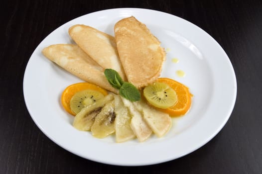 Pancakes with fruit on a white plate.