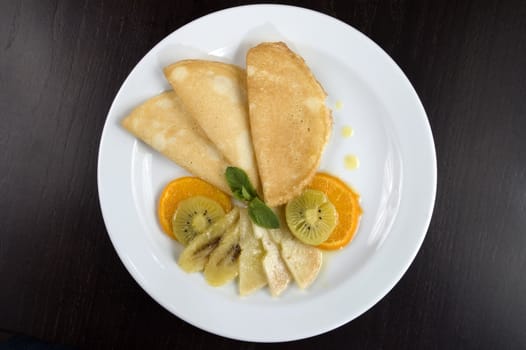 Pancakes with fruit on a white plate.