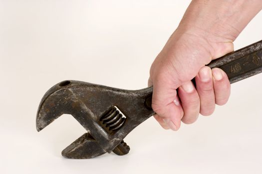 Old spanner in a hand on a light background.