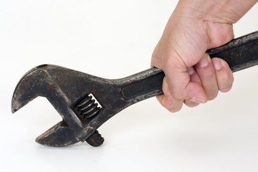 Old spanner in a hand on a light background.