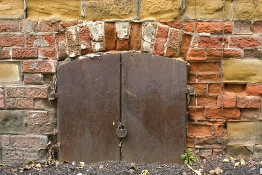 Old brick wall, metal door with the lock.