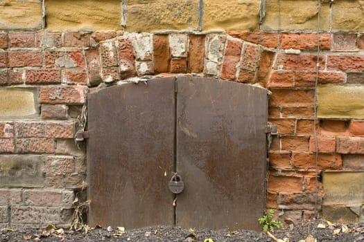Old brick wall, metal door with the lock.