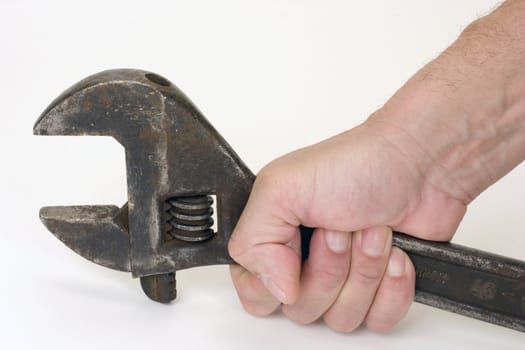 Old spanner in a hand on a light background.
