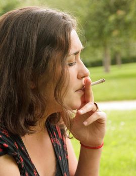 young woman smoking a rolled cigarette, portrait side
