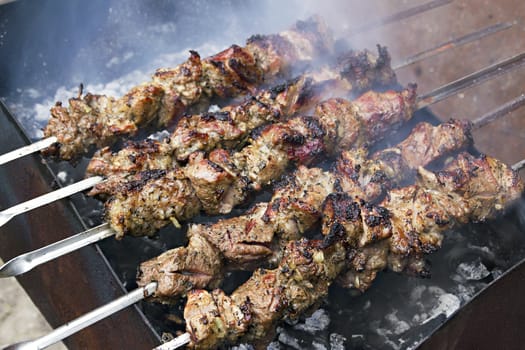 image pieces of meat roasted on a spit over charcoal