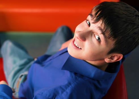 happy teenager sitting on the red sofa in home interior