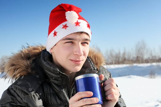 happy young man in santa's hat with travel mug in the winter