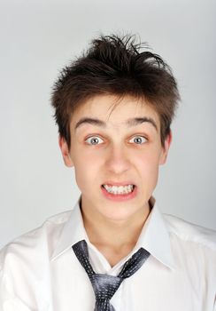 Portrait of Angry and Shaggy Teenager on the Gray Background