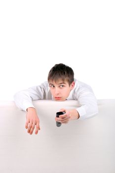 Terrified Teenager with Remote Control hiding behind the Sofa