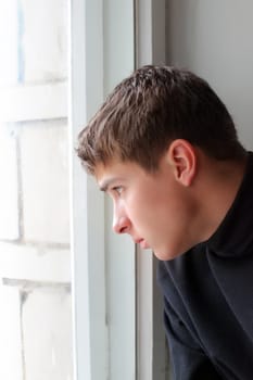Serious Teenager sitting near the Window and waiting for someone