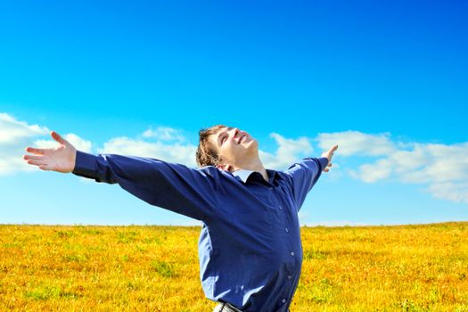 Happy Young Man raising his Hands in the Summer Field