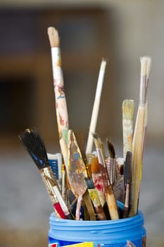Close view of a container filled with used painting pencils.