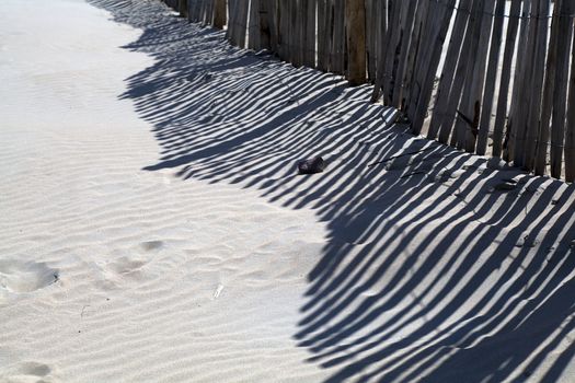 sand texture with striped shadow of the fence