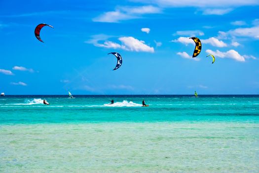 Kitesurfers gliding at high speed around the beach Cinta, Sardinia