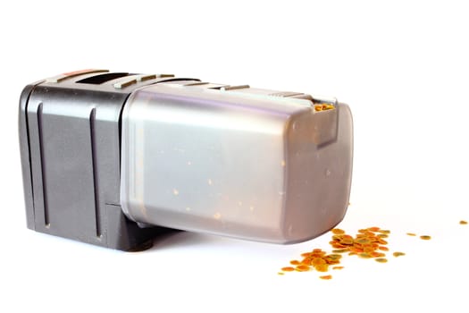 Isolated automatic fish feeder with fish food on the ground.