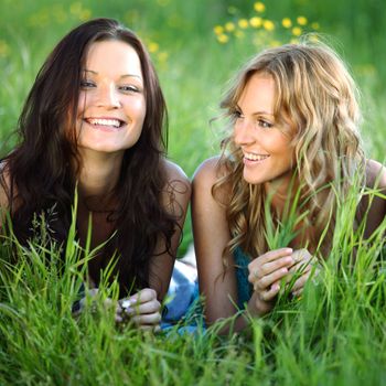 girlfriends lays on green grass and smile