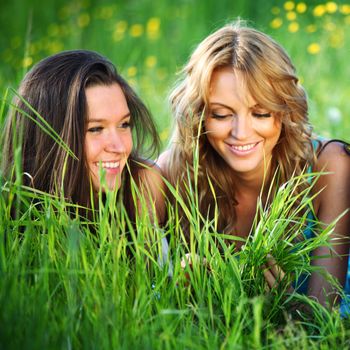 girlfriends lays on green grass and smile