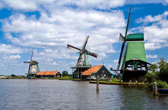 three windmills in Zaanse Schans close to river over beautiful sky