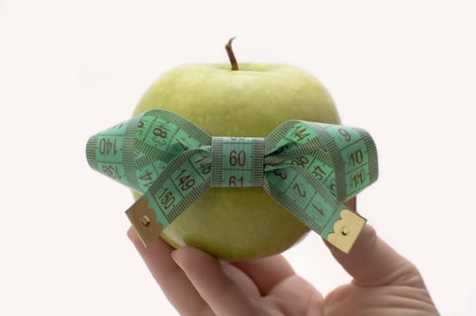 Green apple with measuring tape in a hand.