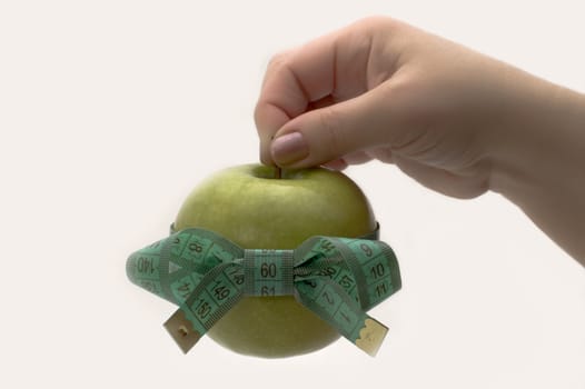 Green apple with measuring tape in a hand.