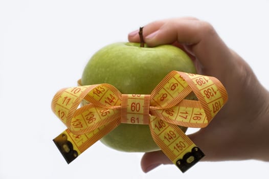 Green apple with measuring tape in a hand.